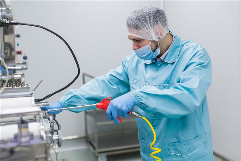 caucasian scientist blue lab uniform configure manufacture machine with shafts control panel close picture